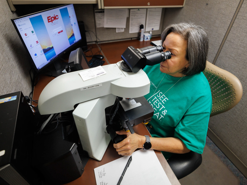 Cytologist Mirna Vargas screens a cervical PAP smear in the microscope for abnormal cells during the April screening event.
