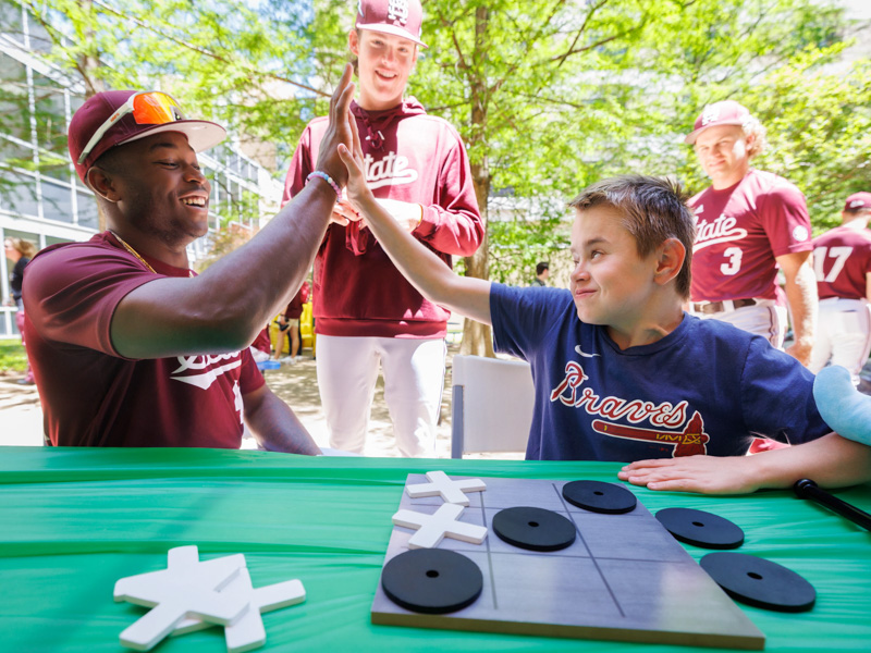 MSU outfielder Dakota Jordan, left, offers a high-five to Sawyer Dykman, of Florence, a patient at Children's of Mississippi.
